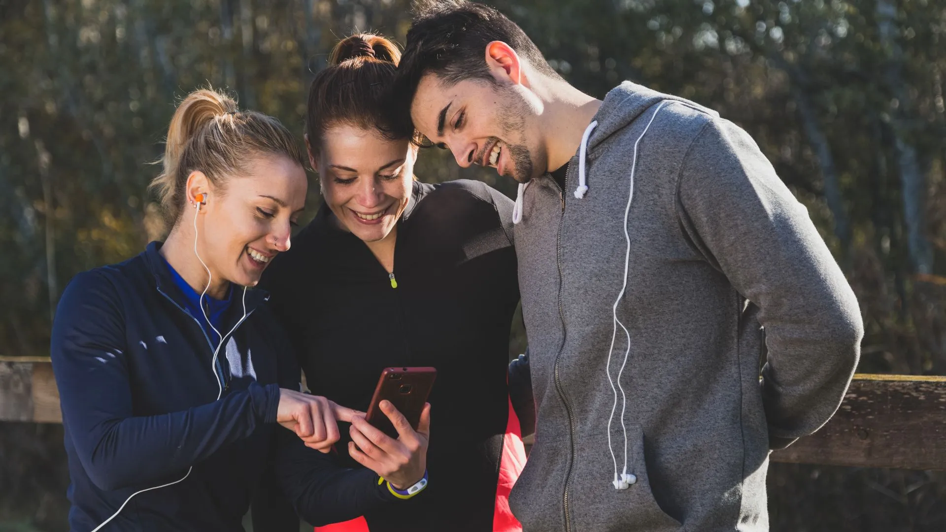 A diverse group of runners comparing different best running applications on their devices.