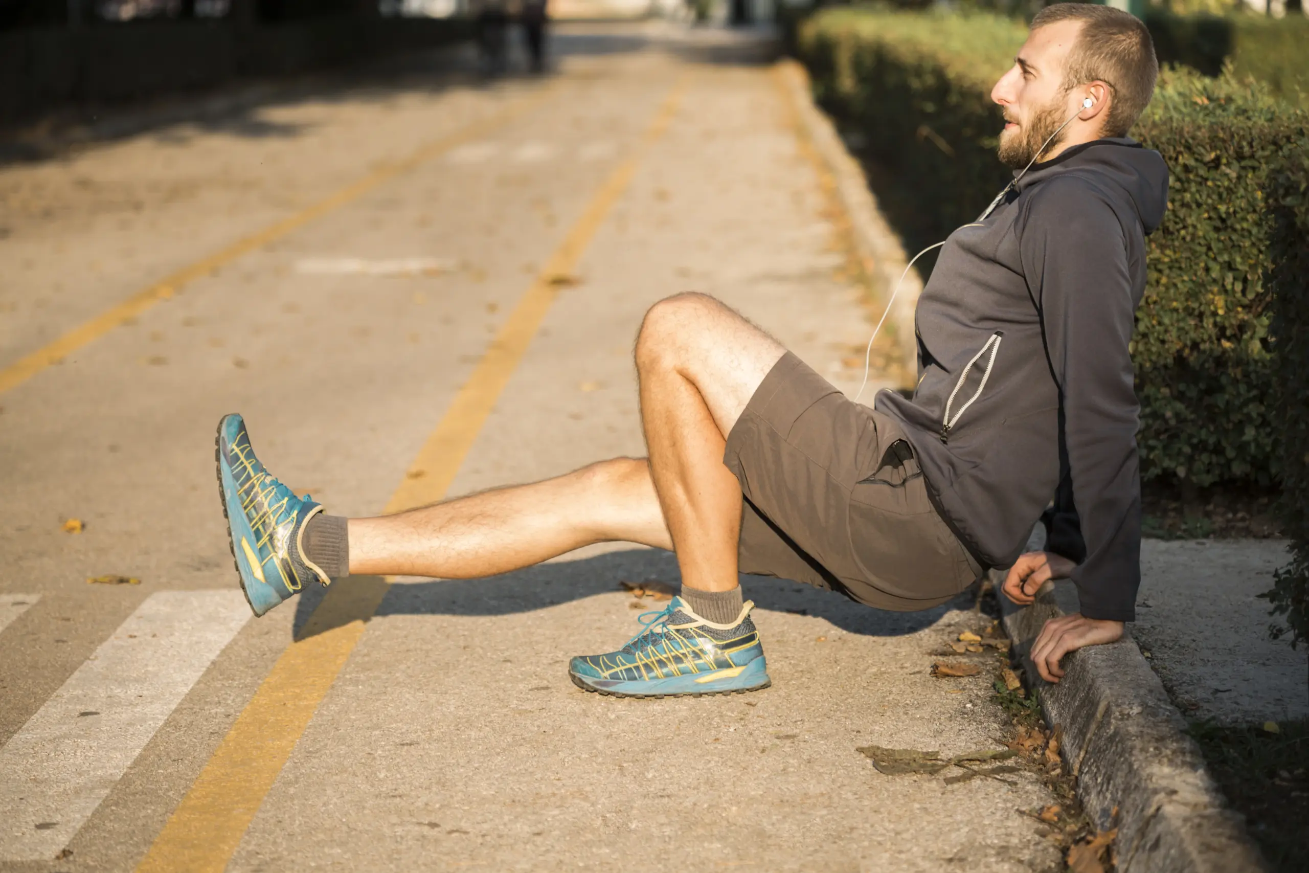Man doing a leg raise exercise on a sidewalk, commonly used to prevent hip impingement in runners.