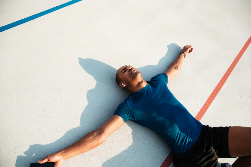 Exhausted runner lying on the ground to begin post marathon recovery.