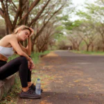 Tired runner resting on the curb to prioritize long run recovery.