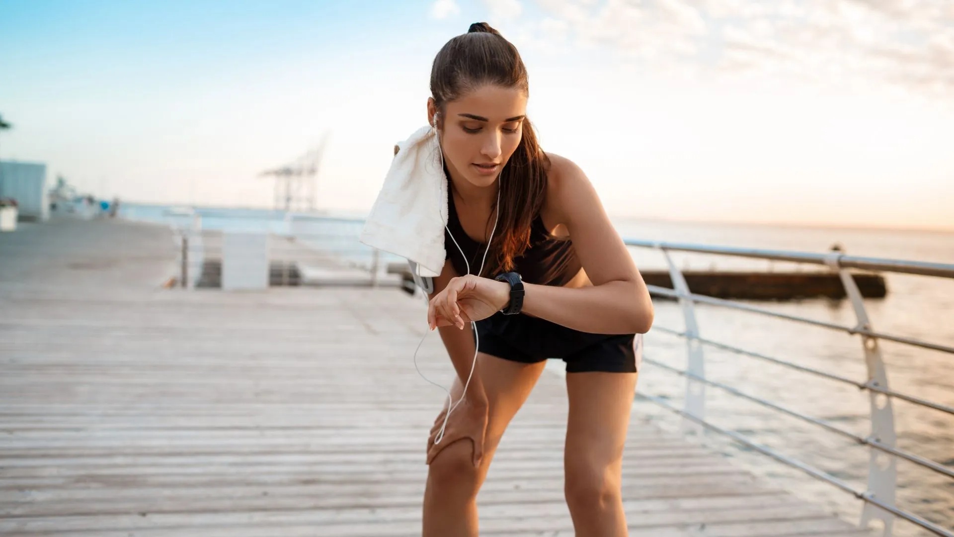 Corredora verifica o ritmo no relógio desportivo, durante treino de resistência.